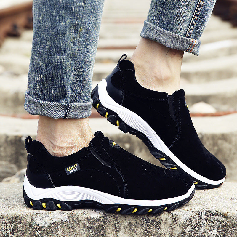 Close-up of black and white slip-on shoes with rugged soles worn with rolled-up blue jeans on outdoor stairs, showcasing Mountain shoes outdoor men's shoes lazy shoes for casual wear.